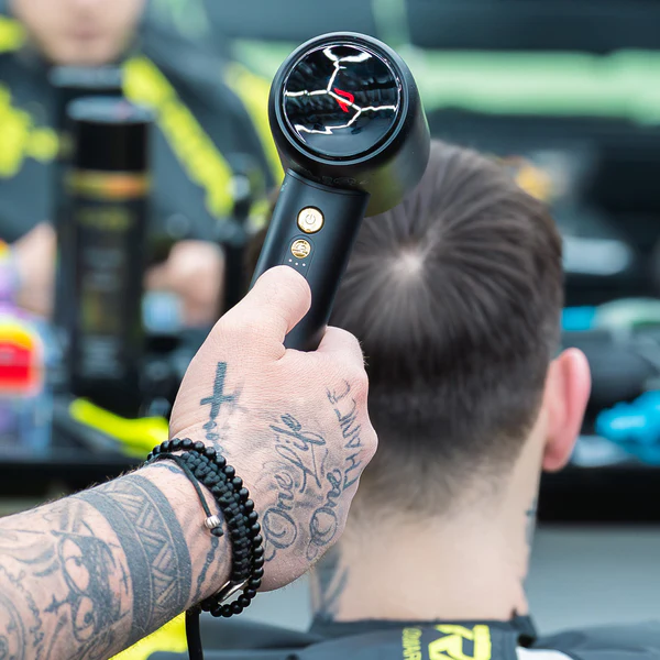 Barber using the Rovra Horus Hair Dryer to style a client's hair in a salon.
