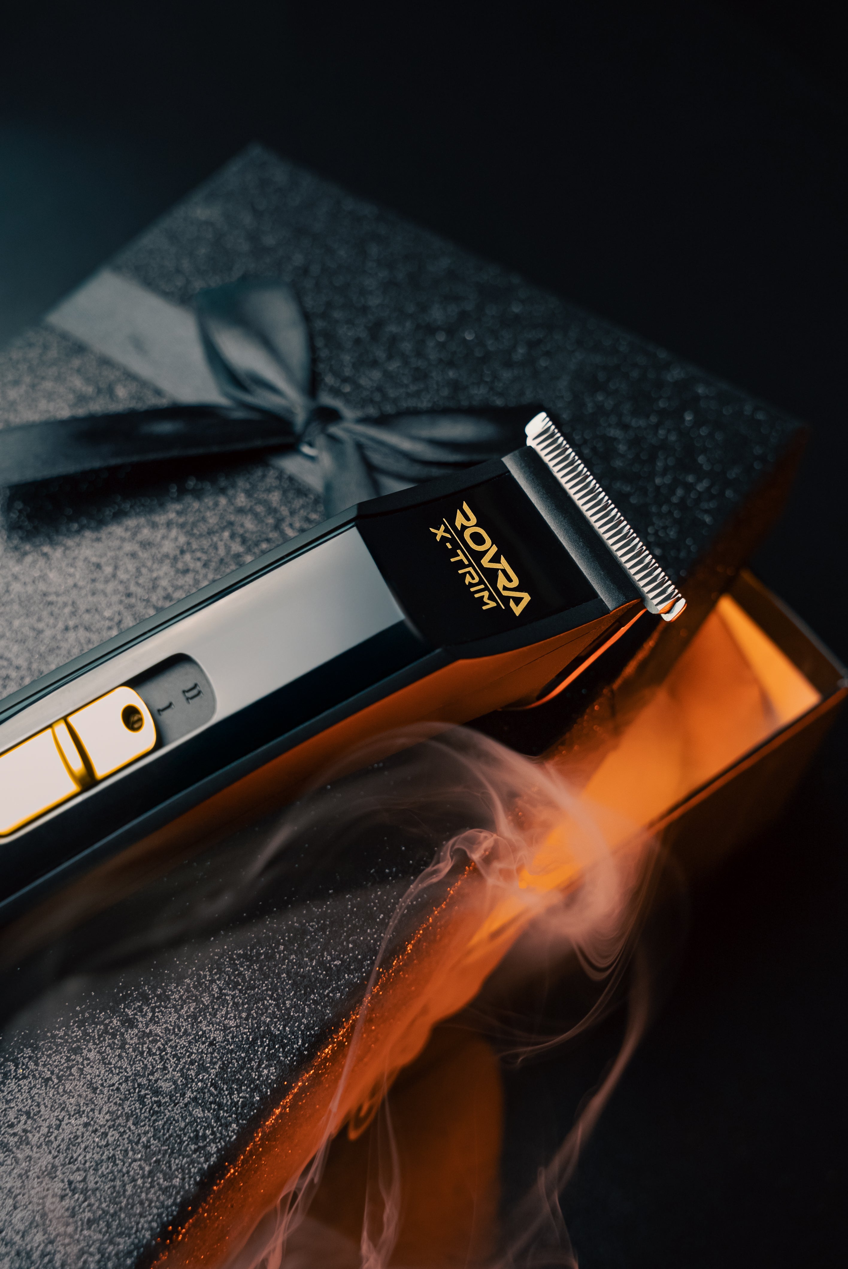 Cordless professional hair trimmer with sleek black design resting on textured gift box with ribbon