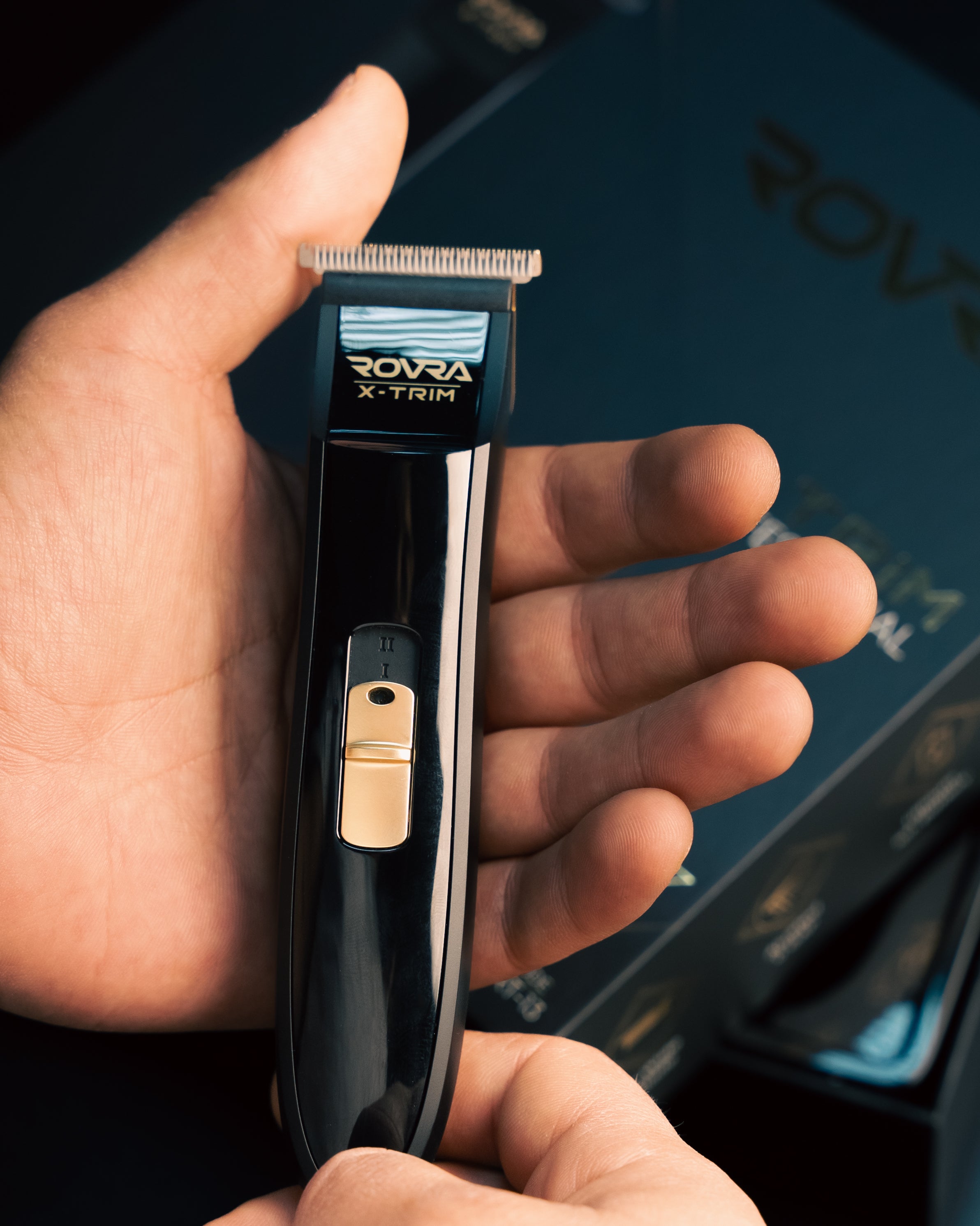 Cordless professional hair trimmer held in hand with black and gold design for precise grooming